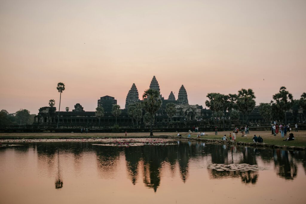 Beautiful sunset view of Angkor Wat with temple reflection in the lake and people enjoying the scenery.